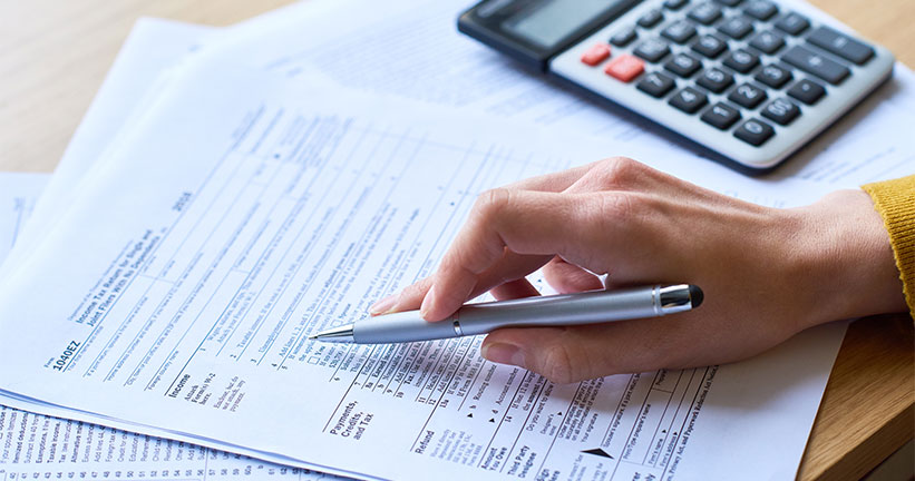 Hand holding pen with calculator 